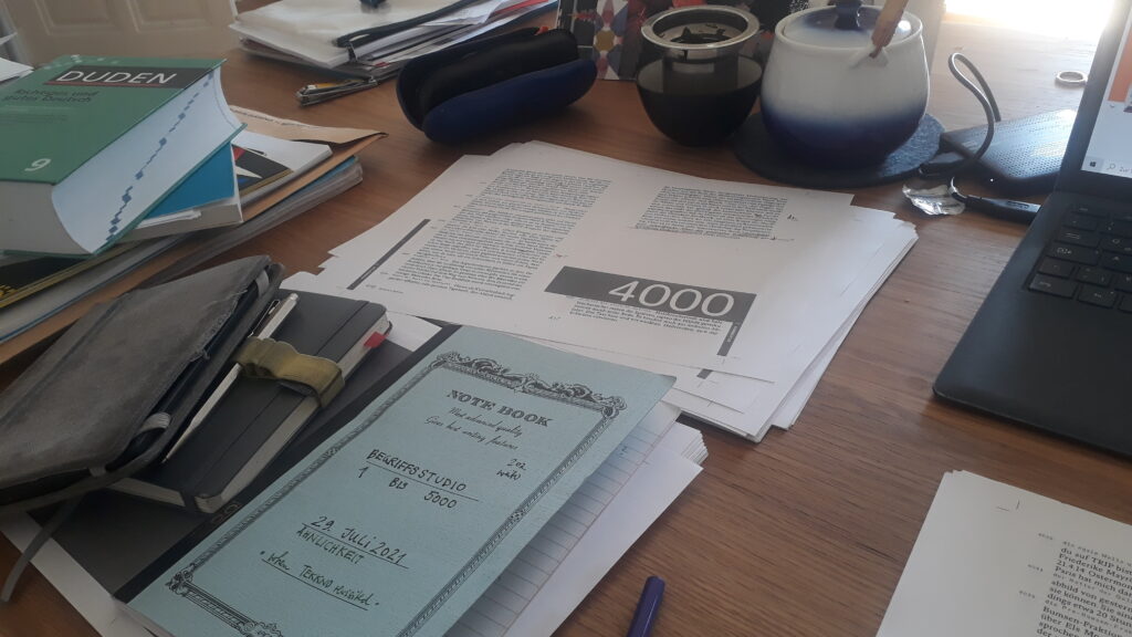 one of Monika Rinck's desks: a table with paper and a booklet titled Begriffsstudio