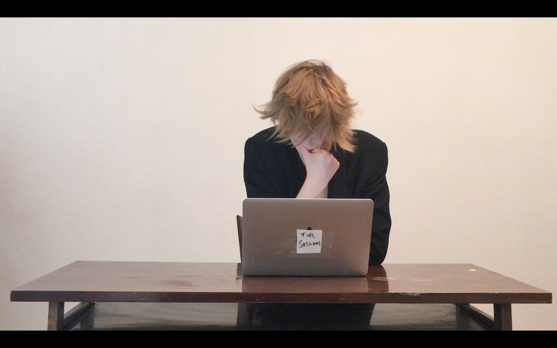 Mara sitting at a desk in front of a computer with the sign Fur Sessions