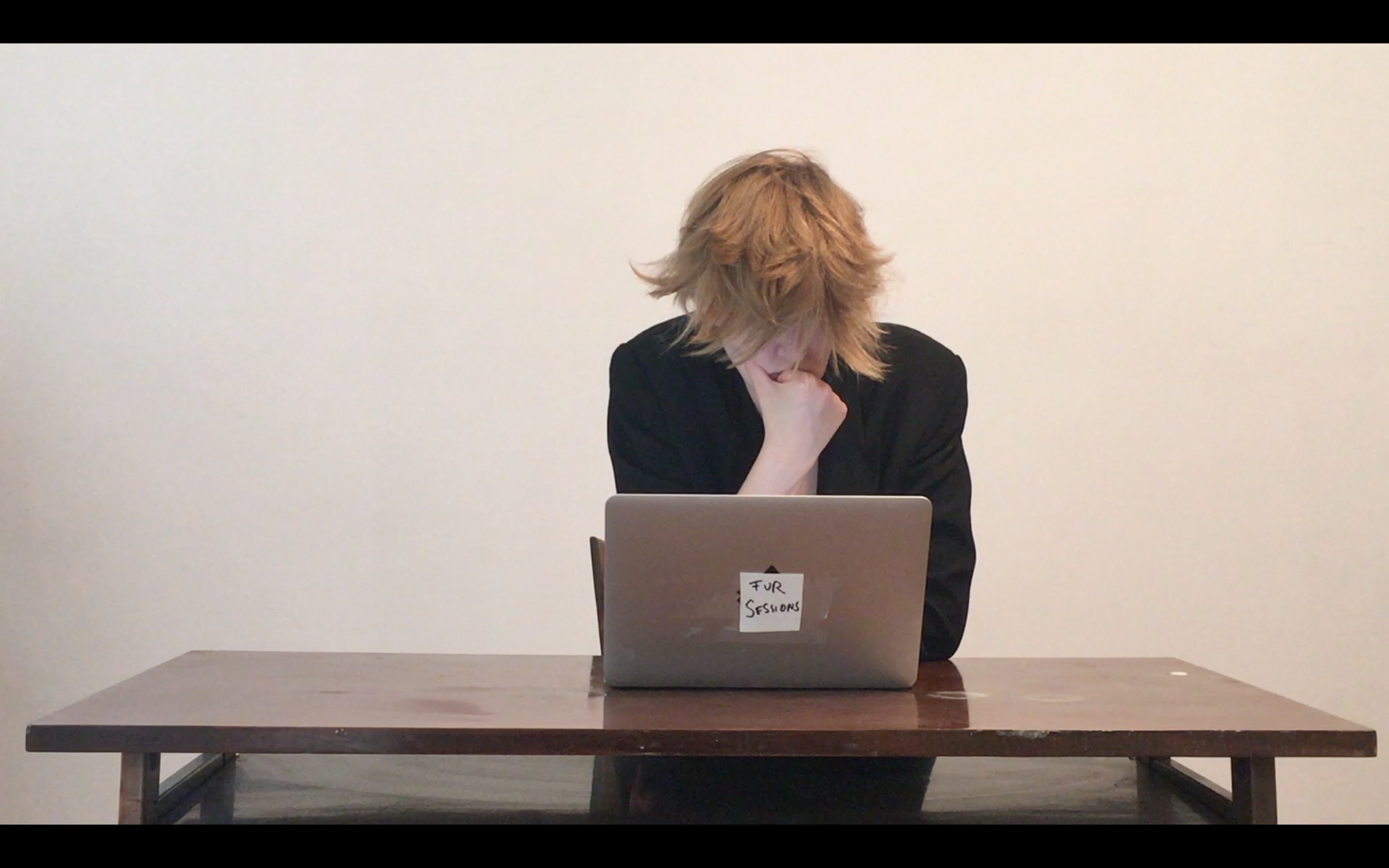 Mara sitting at a desk in front of a computer with the sign Fur Sessions